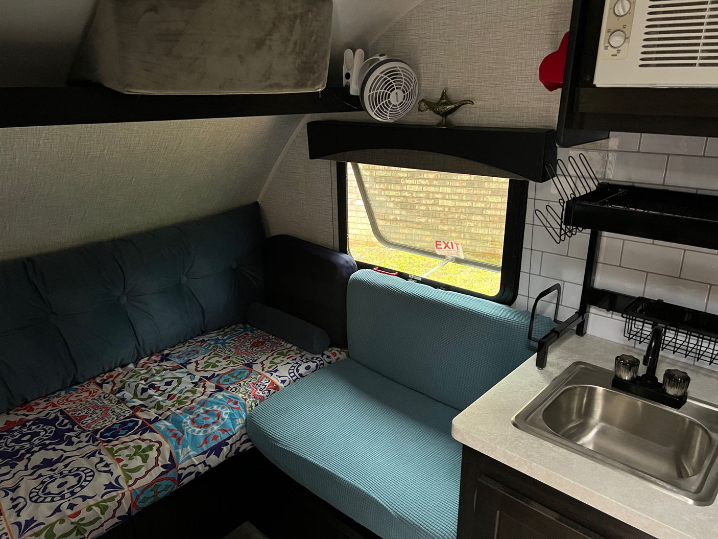 with light blue seating in the foreground.|Cozy RV rental interior featuring a compact kitchenette
