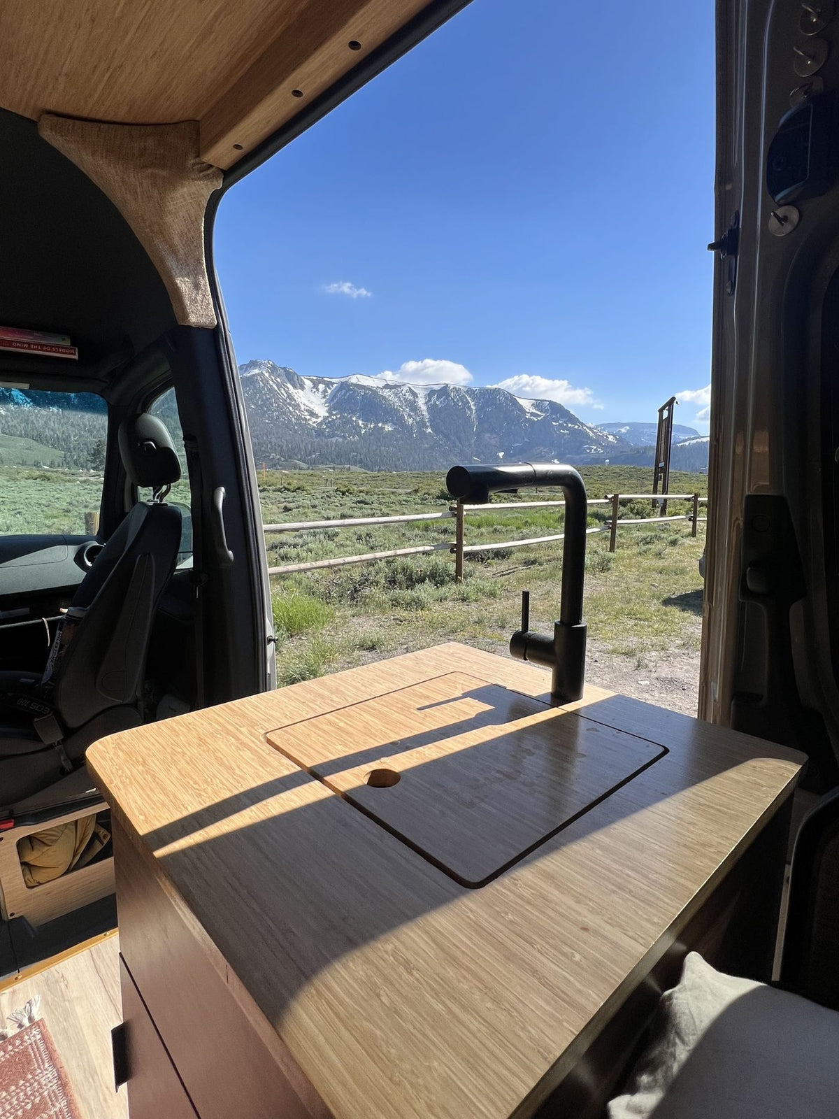 and laptop setup inside a comfy van.|Custom rv rental camper van interior. Rear view shows bench seating — photo 10