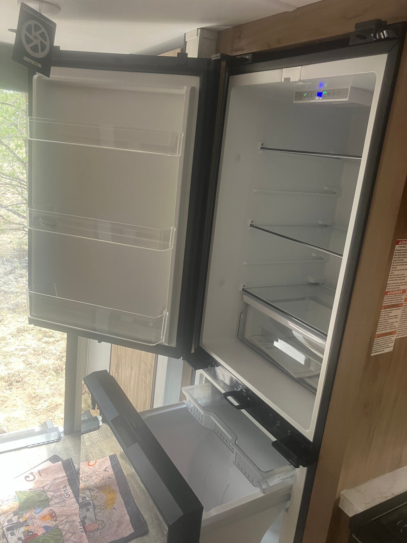 RV rental interior: An open, empty refrigerator and freezer, ready for use, with shelves, drawers, and a digital display. — photo 8