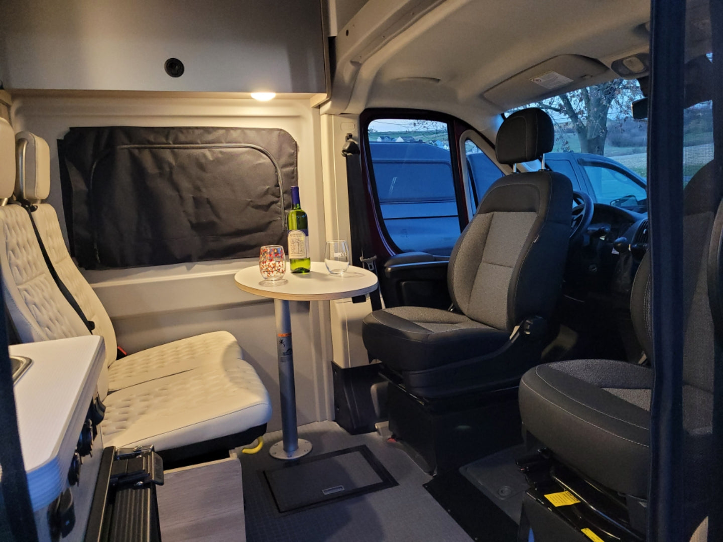 Cozy RV rental interior: A spacious camper van with seating, a table for drinks, and a small kitchenette, perfect for travel.