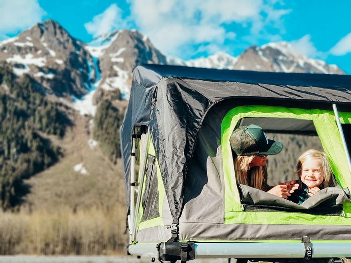 Mom & child in a rooftop tent, offering incredible mountain views. Perfect for your RV rental adventure!