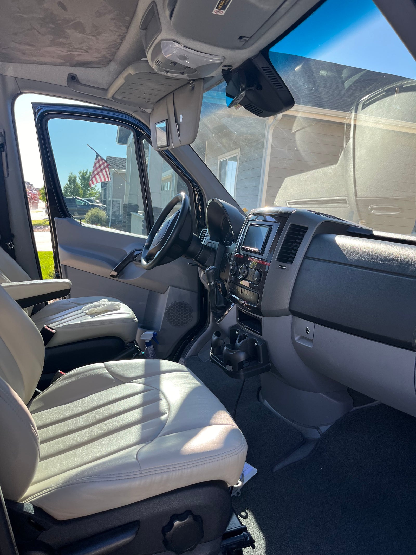 Experience comfort in this RV rental! View of vehicle's roomy interior, light seats, dashboard, and sunlit exterior through windows.
