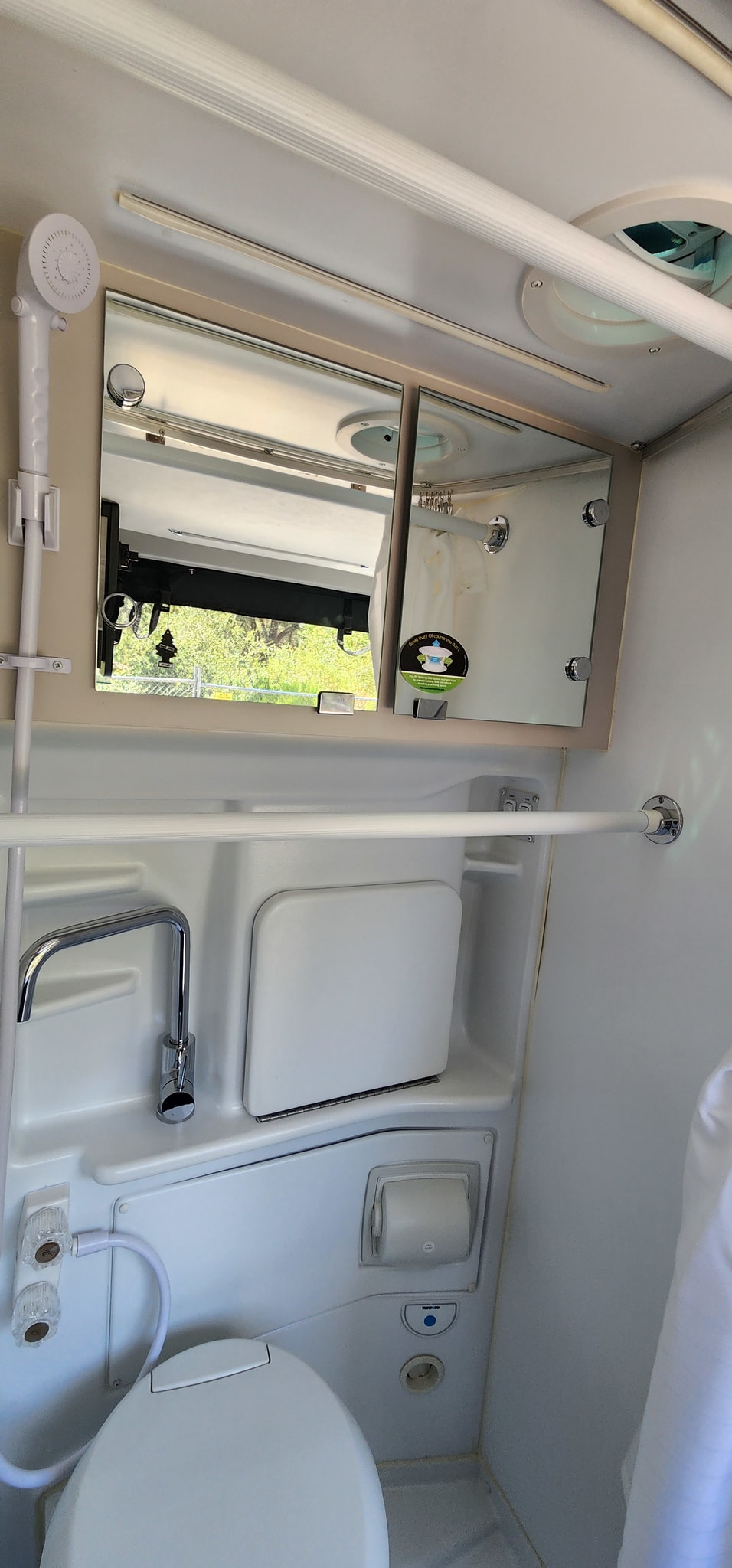 Compact RV rental wet bath with toilet, shower, sink, mirror cabinet, and towel bar in a functional, small space. — photo 5