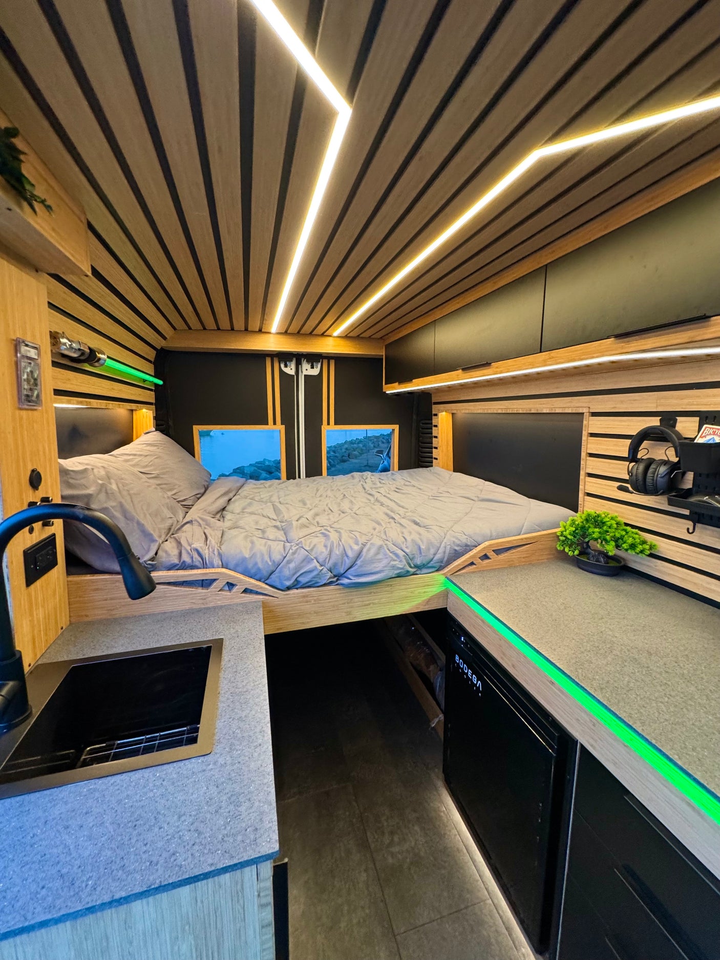 Cozy RV rental interior with a bed, kitchen, and green accent lighting, perfect for van life adventures.