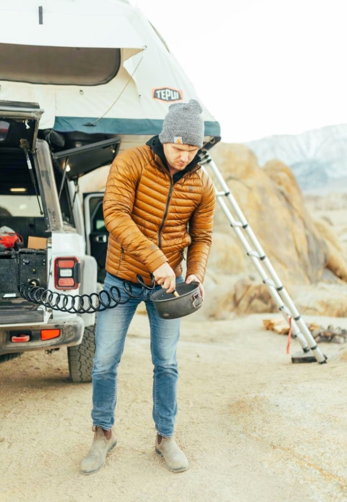 featuring an external water hose for camp life.|Woman organizes overlanding truck with rooftop tent & drawer system. Explore off-grid desert trips with an RV rental setup.|Organizing an RV rental's overland kitchen. This vehicle features a portable stove