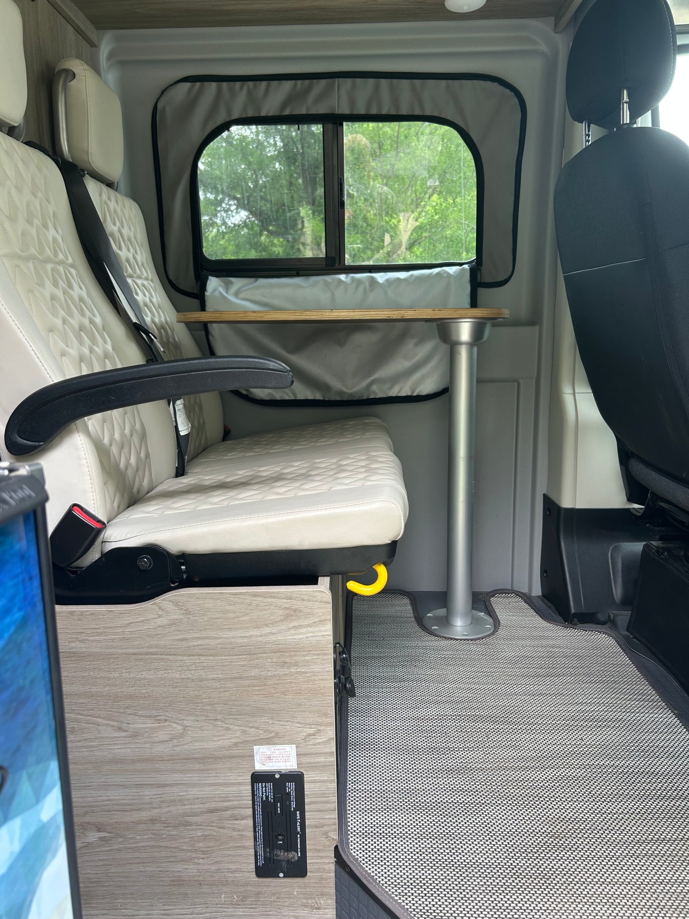 RV rental interior: Cream quilted seats, a removable table, and a vital SAFE-T-ALERT propane alarm for safety.