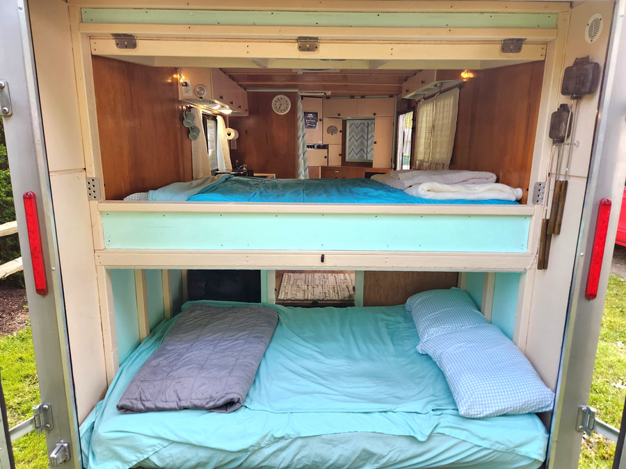 Cozy RV rental interior featuring comfortable bunk beds with blue bedding, perfect for a family adventure.