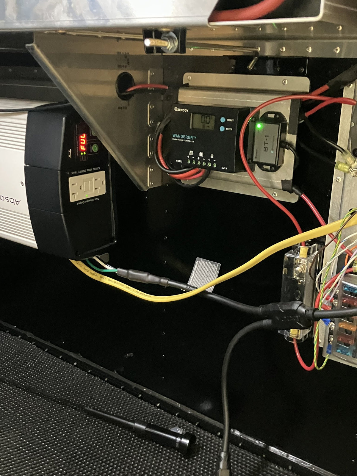 Electrical bay of the 2023 Mammoth Overland ELE: Renogy Wanderer solar charge controller with a BT-1 Bluetooth module, fused distribution block and busbar, and an inverter with a GFCI outlet, wired inside the cabin — photo 4