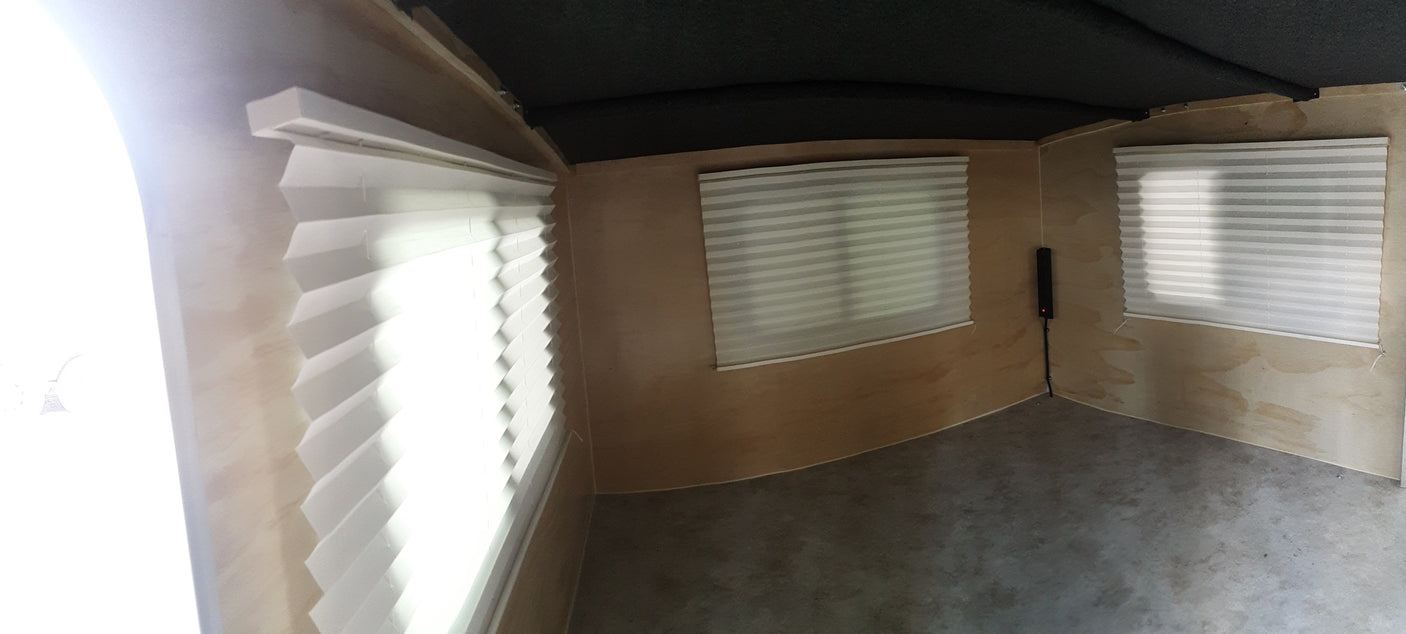 under an awning. A woman enjoys the sunny outdoors.|Interior of an RV rental: light wood walls