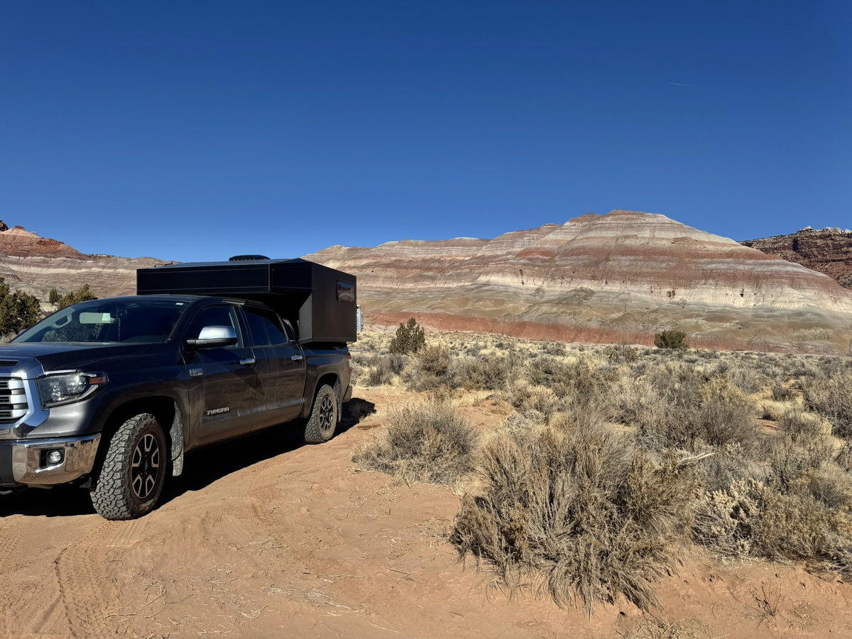 The Moonlander X camper and Tundra parked on red dirt in front of banded desert hills — photo 9