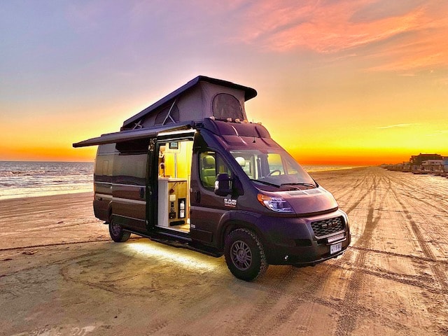 tire tracks. Perfect beach adventure.|Dark grey camper van with open side door