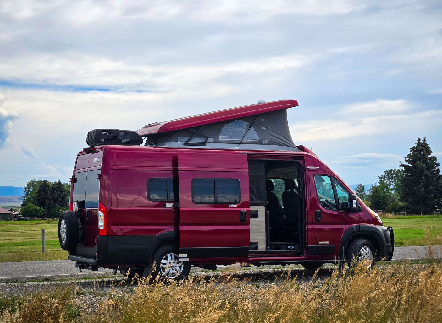 Red Winnebago Solis camper van with pop-top extended and side door open, perfect for an RV rental adventure.
