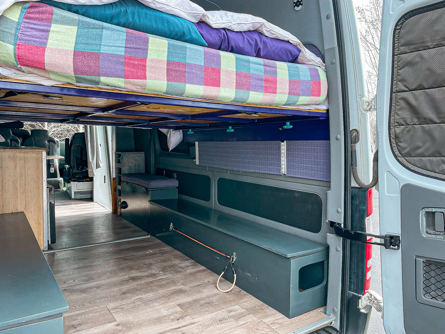 Spacious RV rental interior from the rear, showing a raised bed, built-in storage, and wood flooring.
