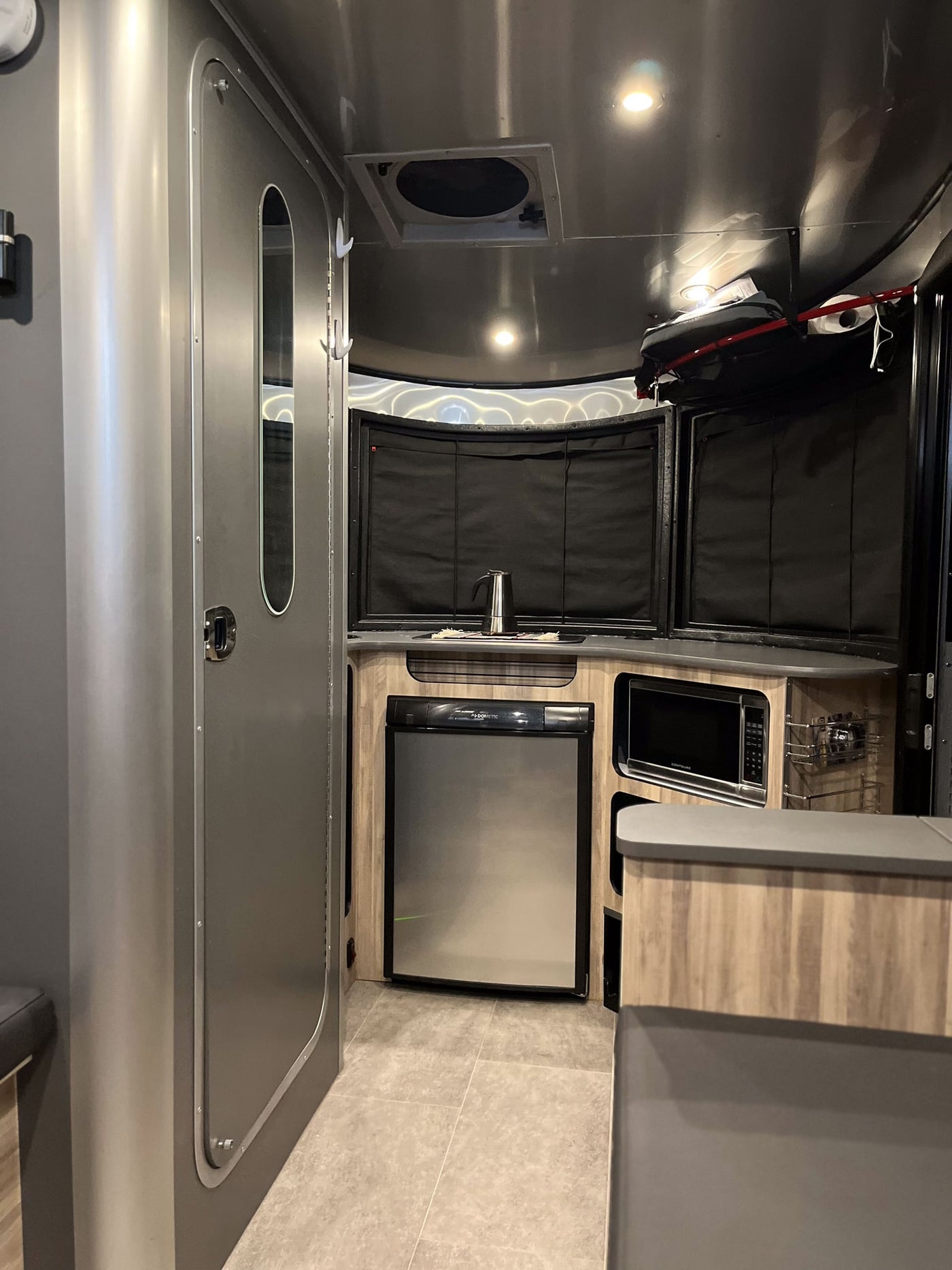 Step inside this modern RV rental! Featuring a sleek kitchen with fridge, microwave, and ample counter space for your travels. — photo 10