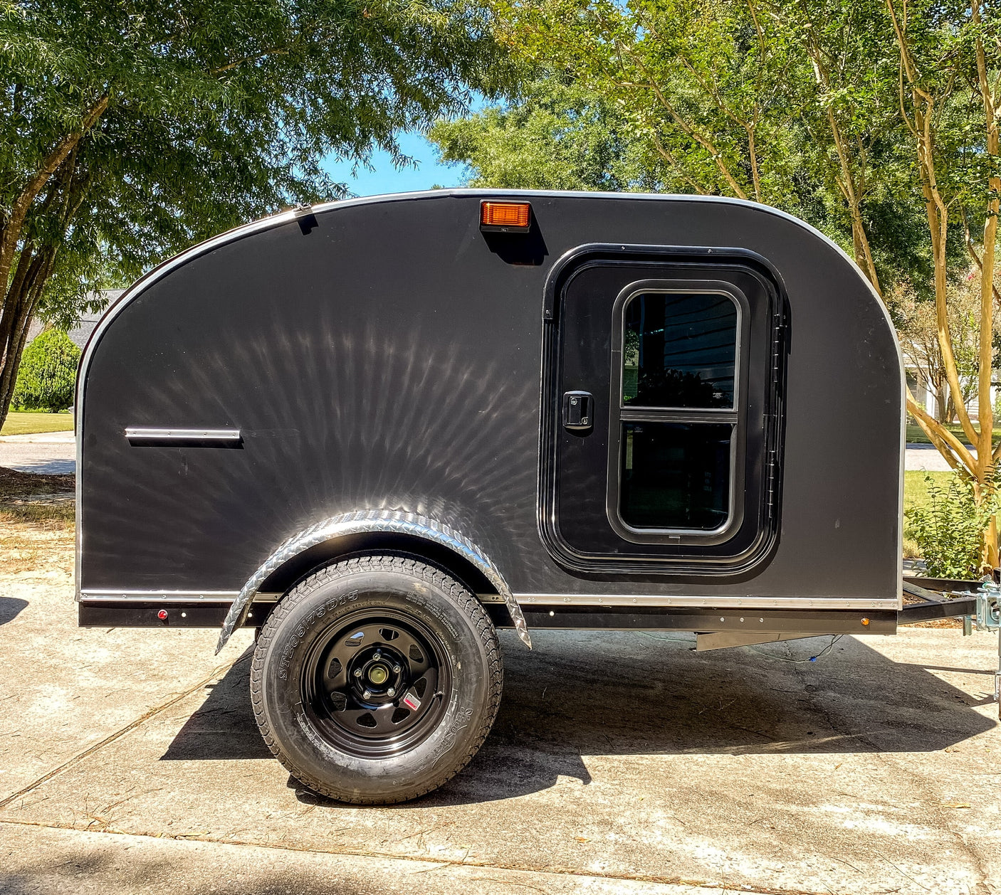 perfect for outdoor **road trip** adventures.|Black teardrop camper ready for rv rental. Features a spacious light wood interior