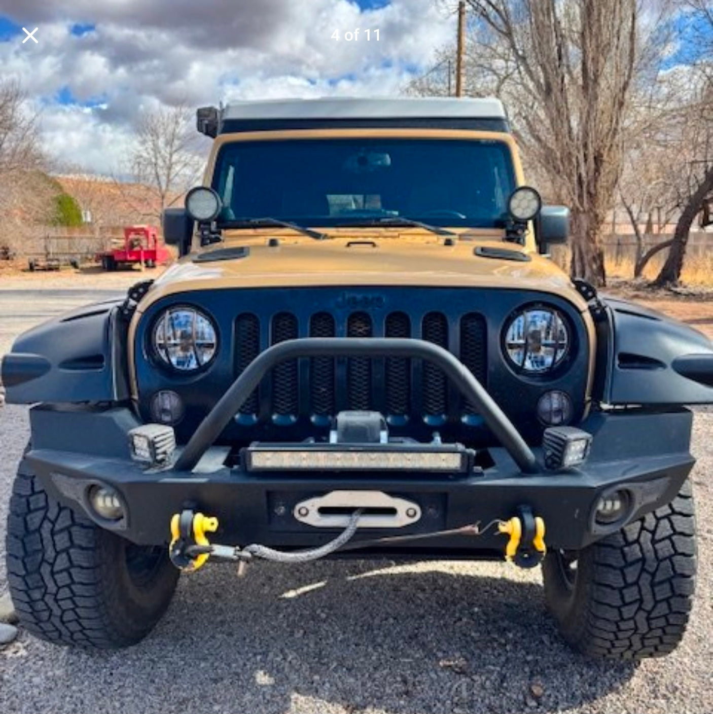 revealing a breathtaking view of red rock mountains and snow-capped peaks.|Yellow Jeep Wrangler with an RV awning
