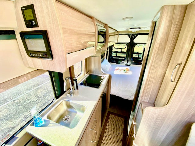 and fridge. Ideal for travel.|RV rental interior featuring a compact kitchen with sink/stovetop