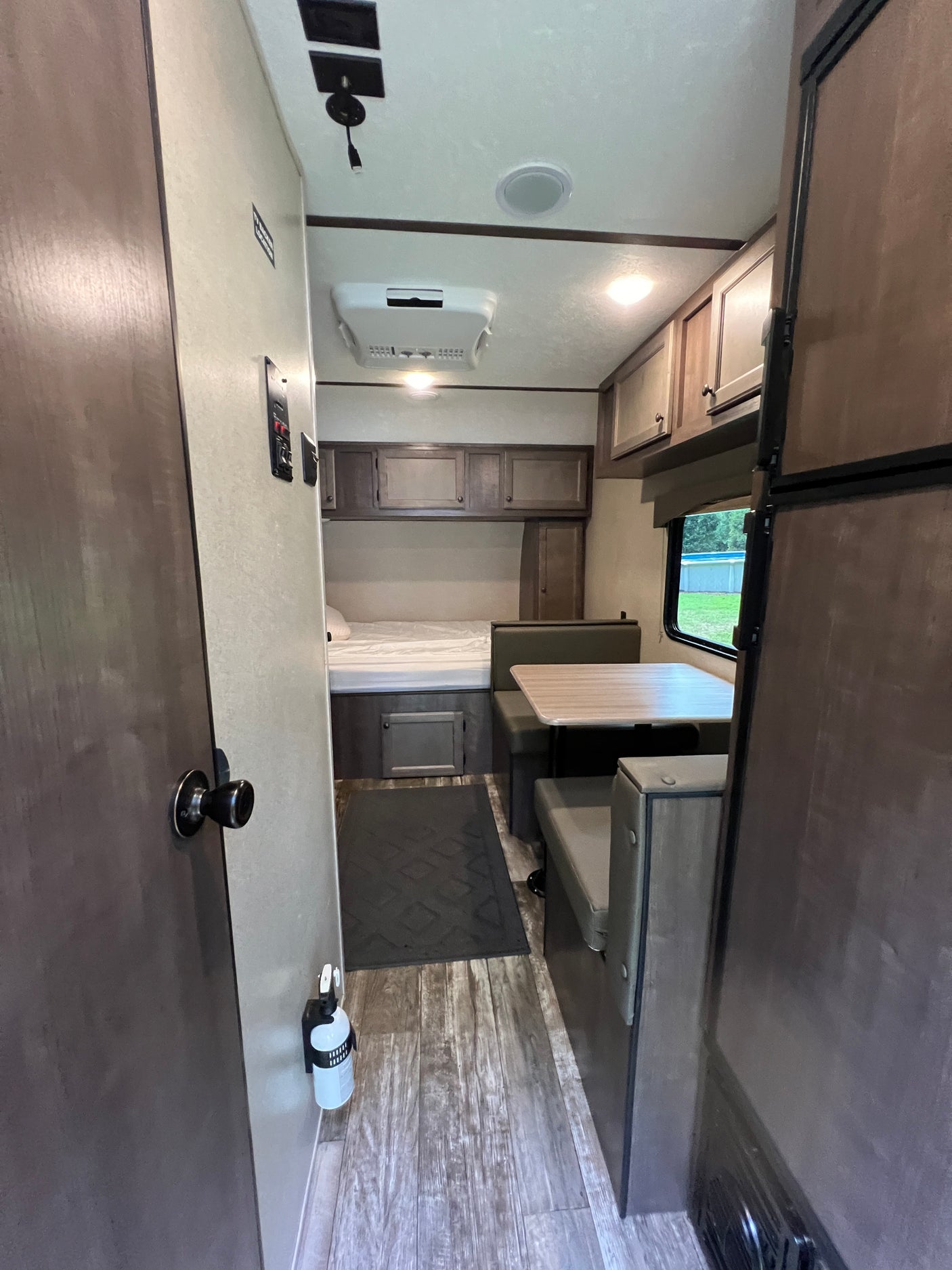 This RV rental interior showcases a cozy bedroom, versatile dinette, and compact kitchen area. Note the on-board amenities.
