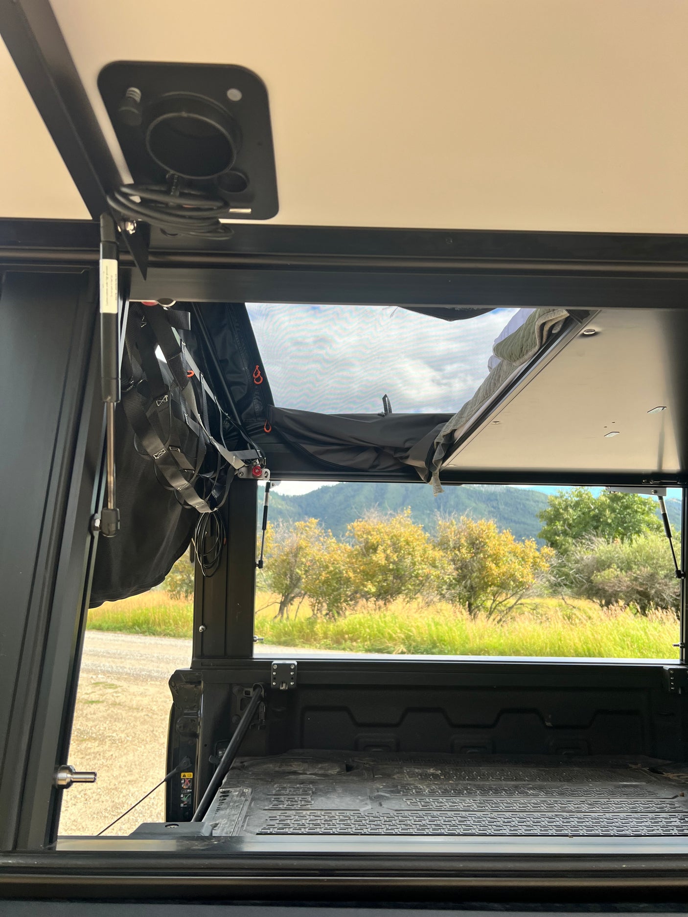Relax inside this RV rental truck bed camper. An open pop-top and mesh window offer serene views of mountains and nature.