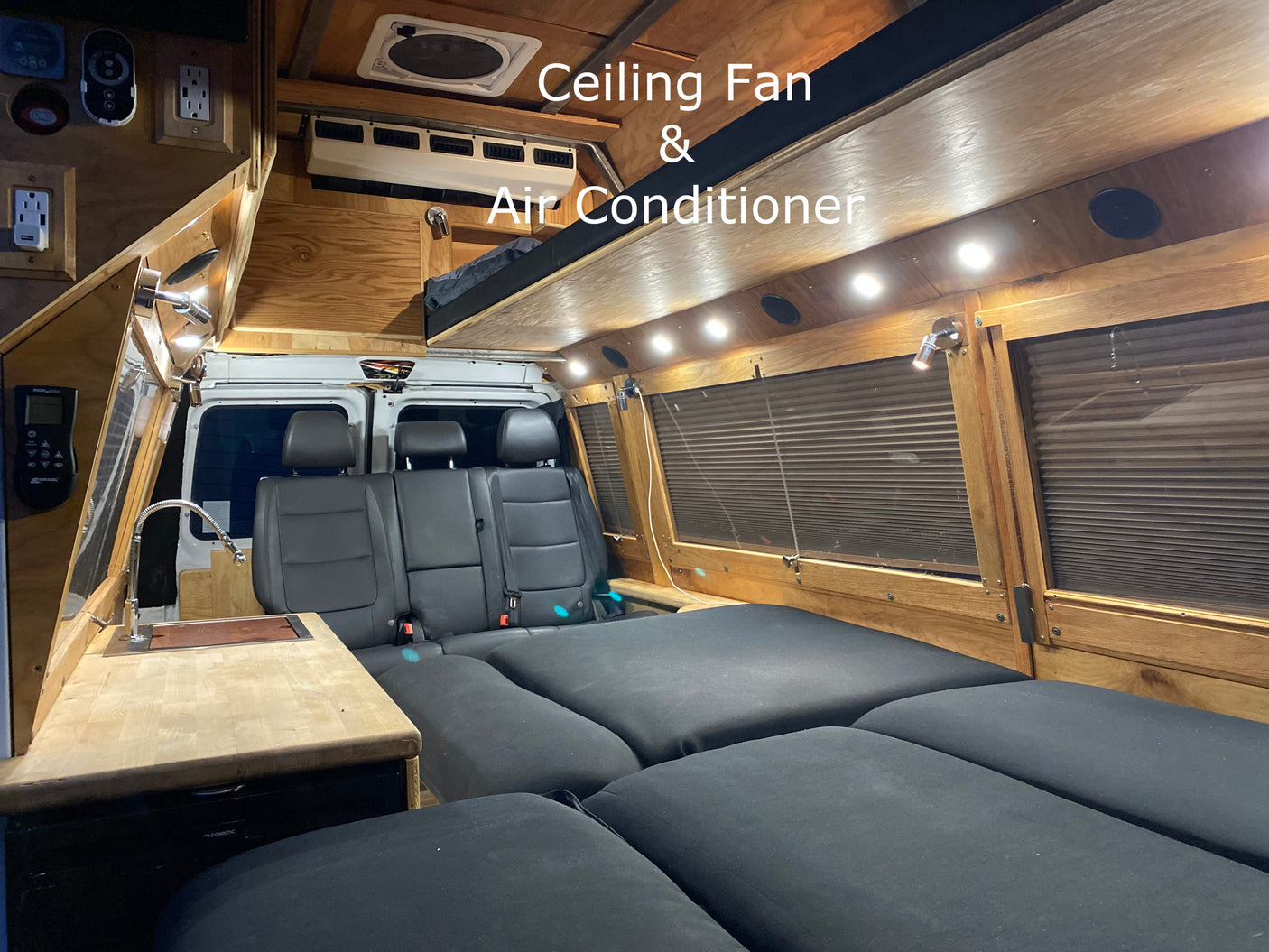 This RV rental's custom interior boasts a wood-paneled ceiling with a fan & AC, ambient lighting, kitchen sink, and versatile seating/bed.