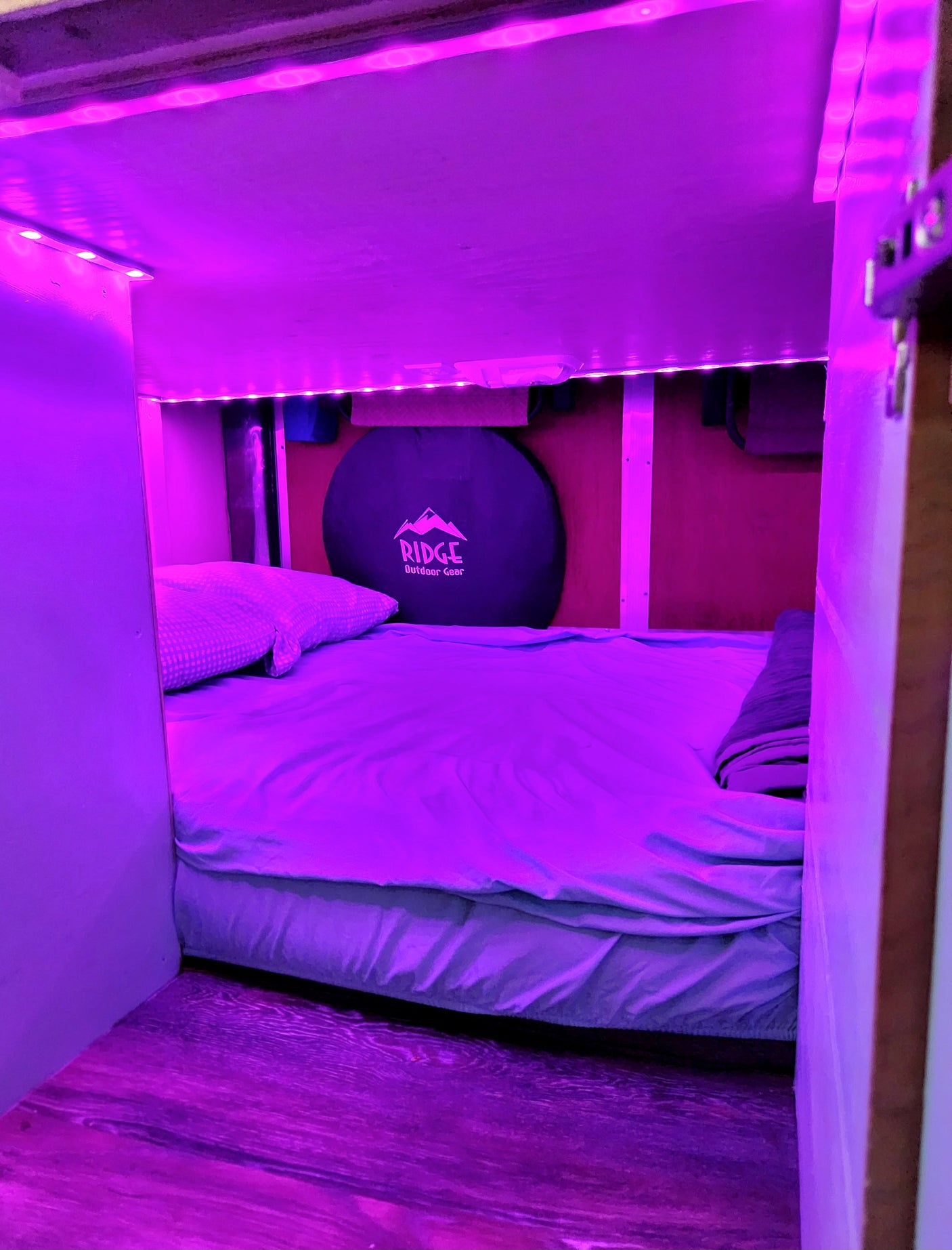 RV rental: vibrant purple LED-lit sleeping space with a comfy bed and RIDGE outdoor gear.