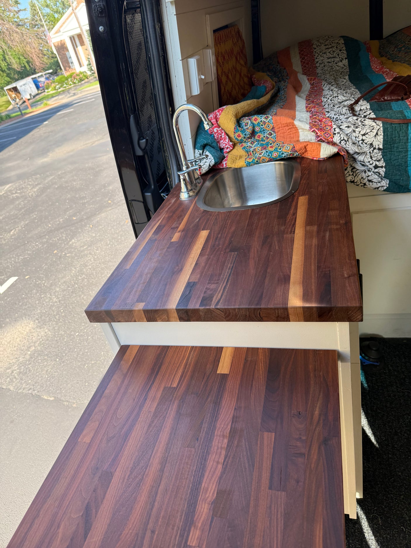 Inside an RV rental, a sleek wooden countertop with a sink and faucet. Perfect for compact mobile kitchen setups.