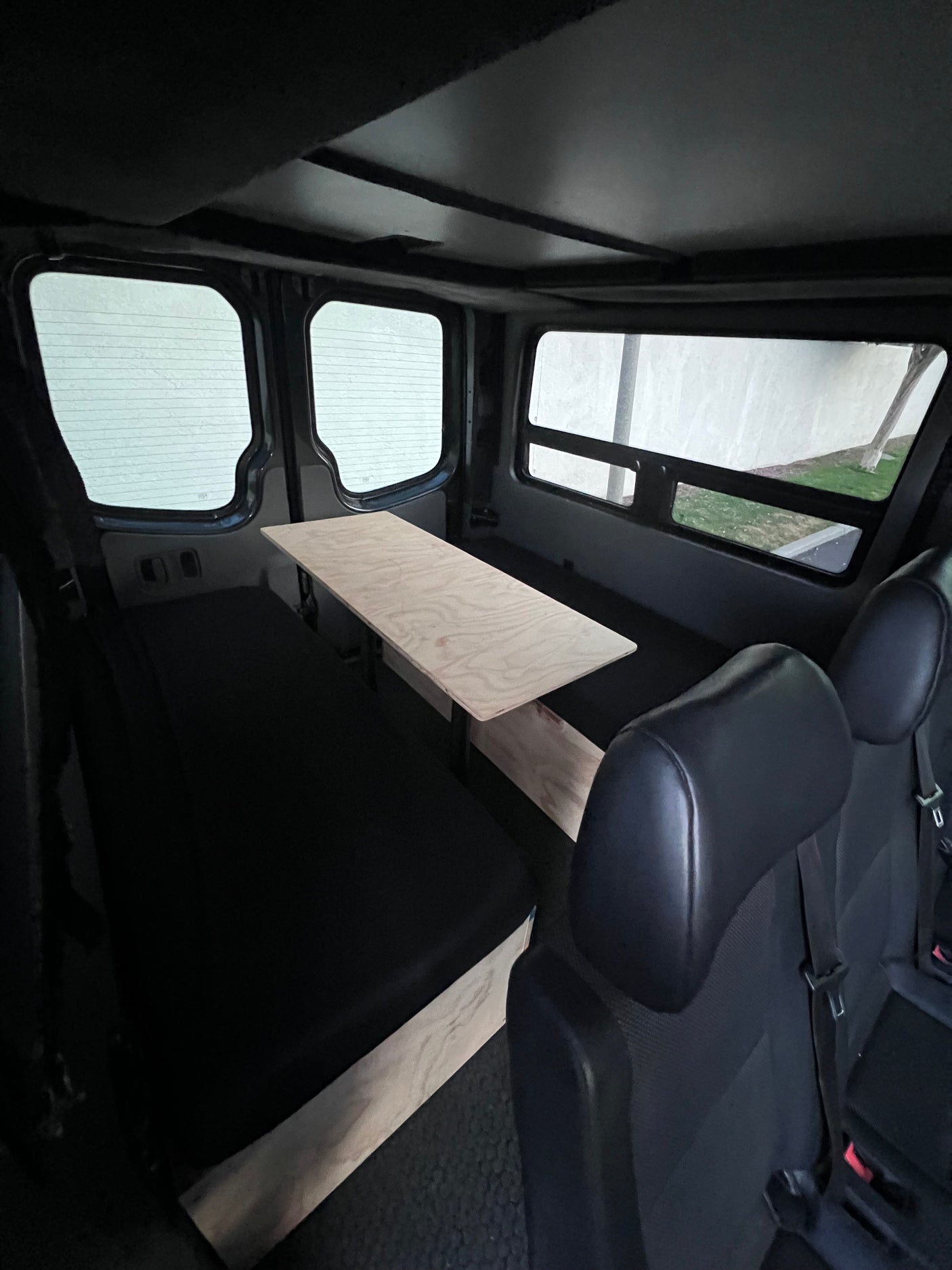 This RV rental features a functional interior with a light wood table, black padded benches, and large windows.