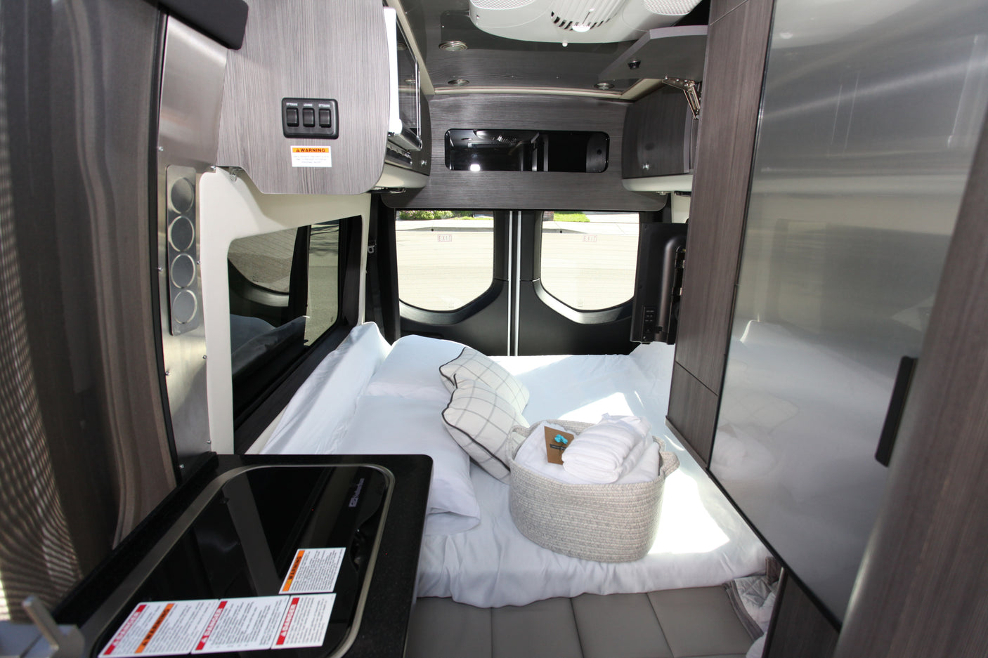 Step inside this modern RV rental showcasing a compact kitchen, comfy bed, and clever storage solutions for your adventure.