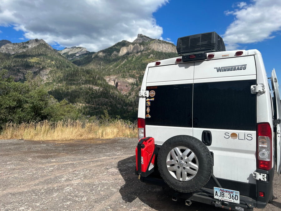 ready for adventure.|A campfire with smoke and a white RV rental camper van parked in a scenic outdoor setting at sunset.|This white pop-top camper van