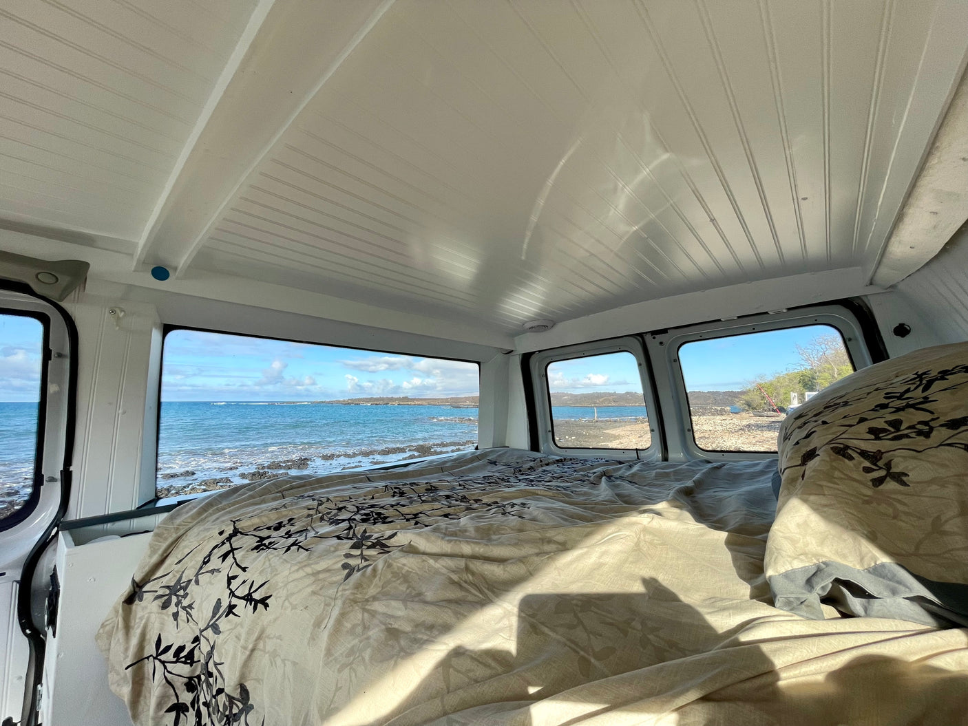 Serene ocean view from a comfortable bed in an RV rental. Ideal for beachfront adventures in a camper van.