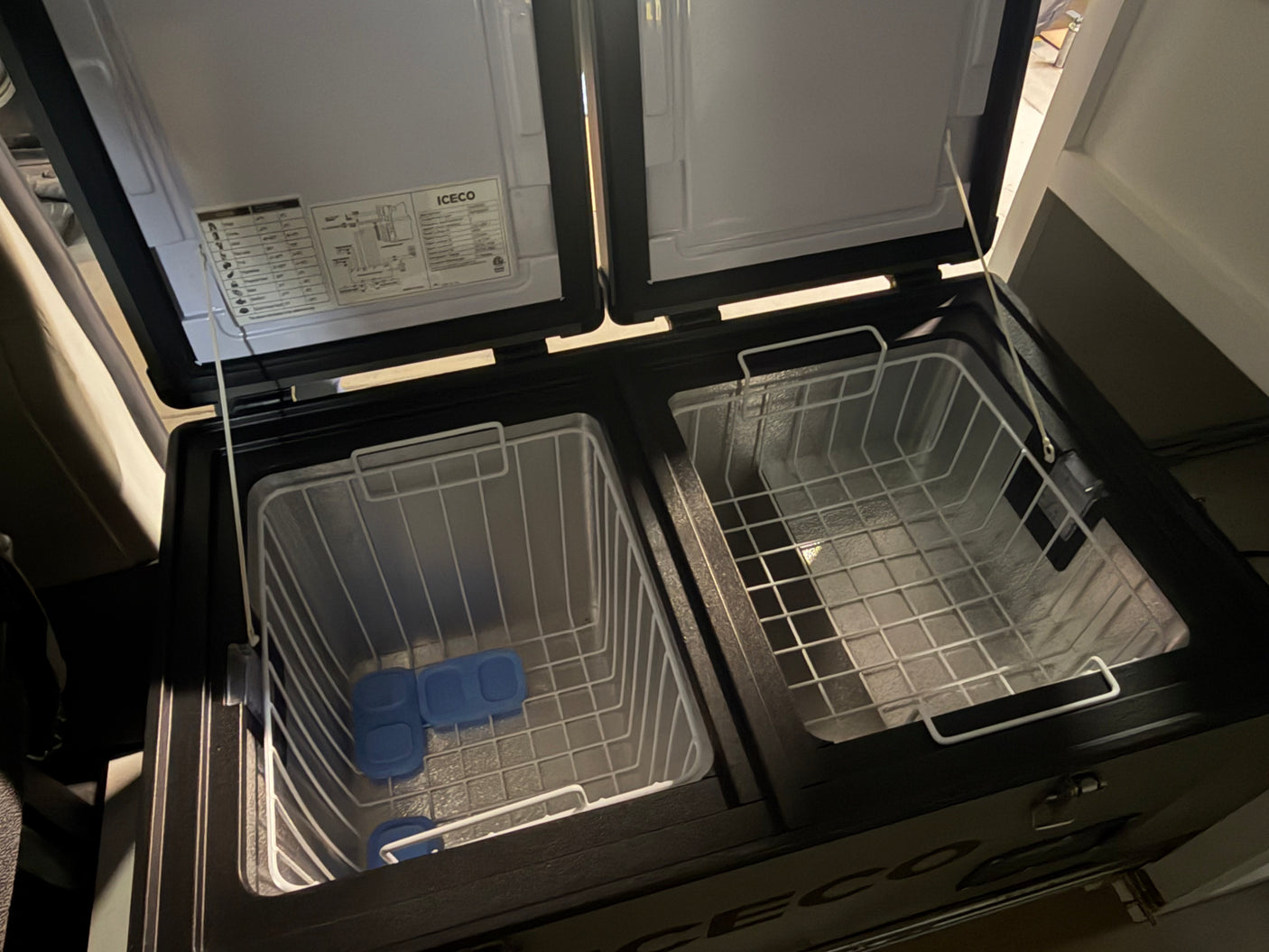Open dual-zone portable fridge/freezer with wire baskets and ice packs, ideal for your RV rental or camping adventure.