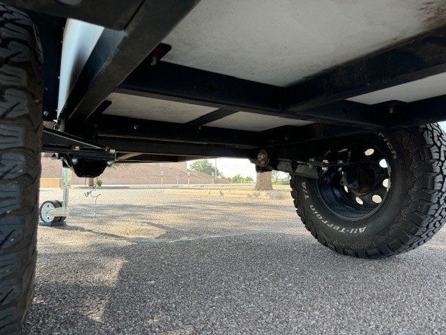 beside a ladder.|Equipped RV rental: portable water and shower system featuring a green jerry can