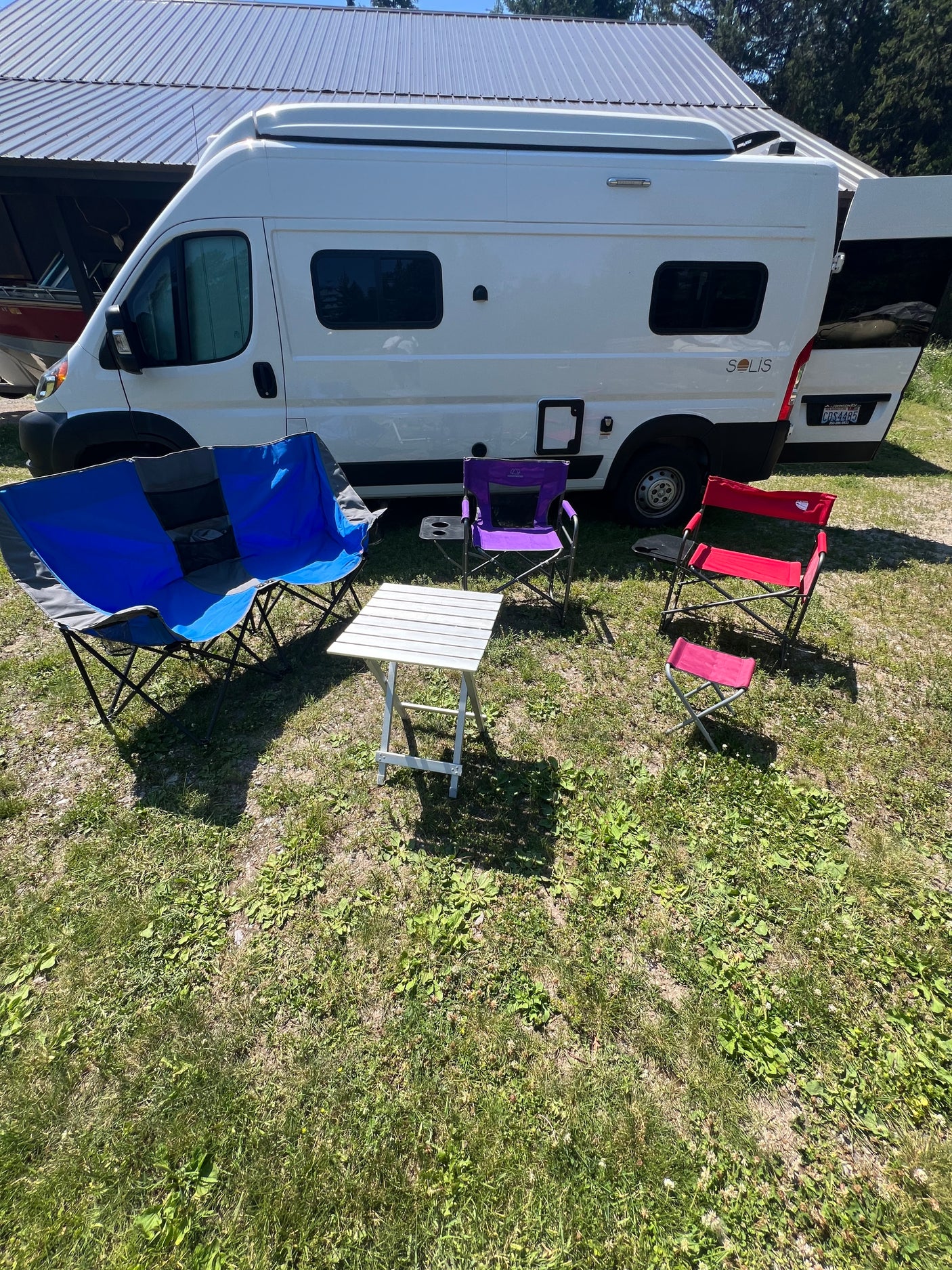 White Solis RV rental parked on grass, surrounded by colorful camping chairs and a small table. Ready for outdoor living.