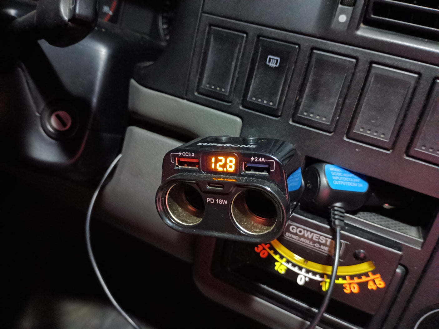 RV rental interior with a multi-port power adapter showing 12.8V, USB charging ports, and a GOWEST inclinometer.