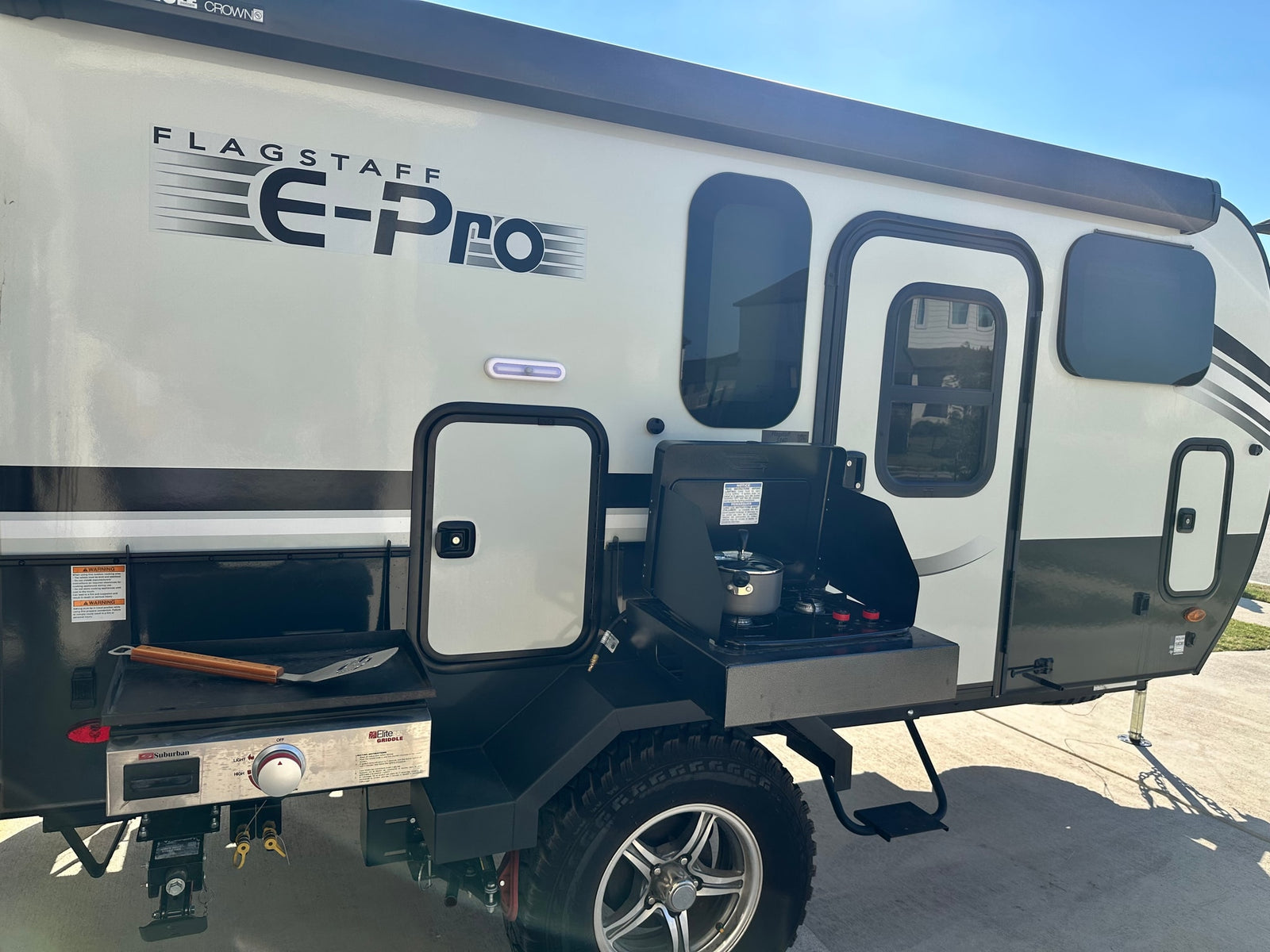 This Flagstaff E-Pro RV rental features an outdoor kitchen with a Suburban griddle and a two-burner stove.