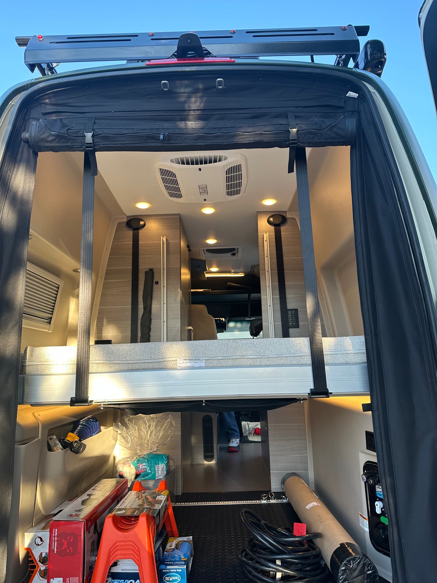This RV rental showcases its spacious rear interior with a raised bed, ample storage for camping gear, and a view of the cabin.