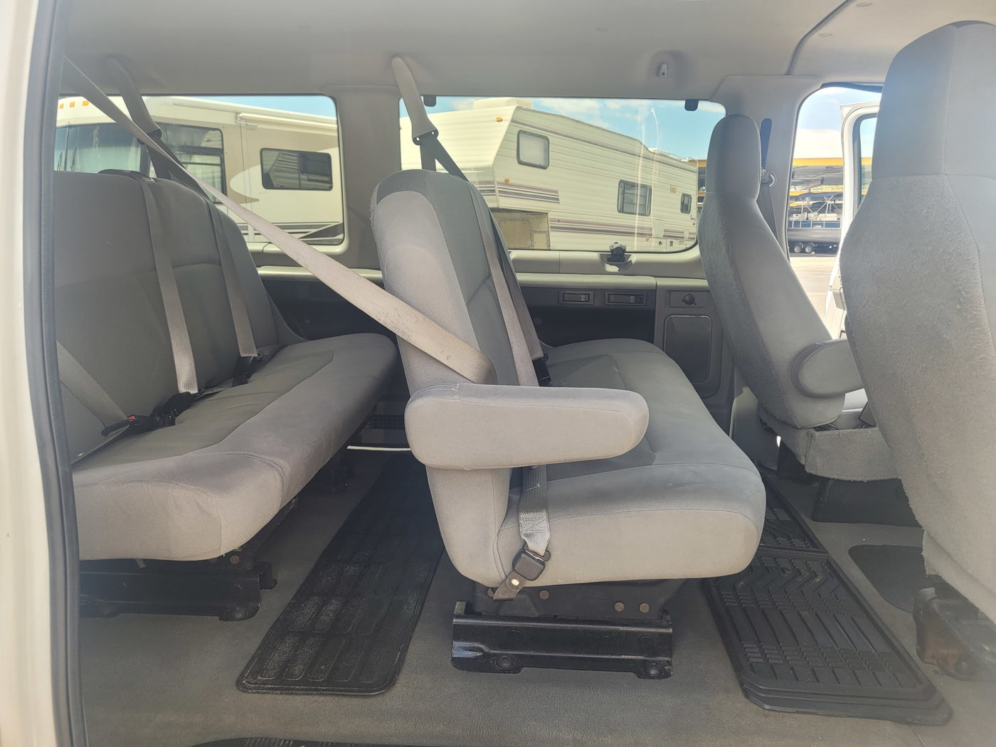 RV rental vehicle's grey interior with passenger seating. Large RVs are visible parked outside through the windows. — photo 11