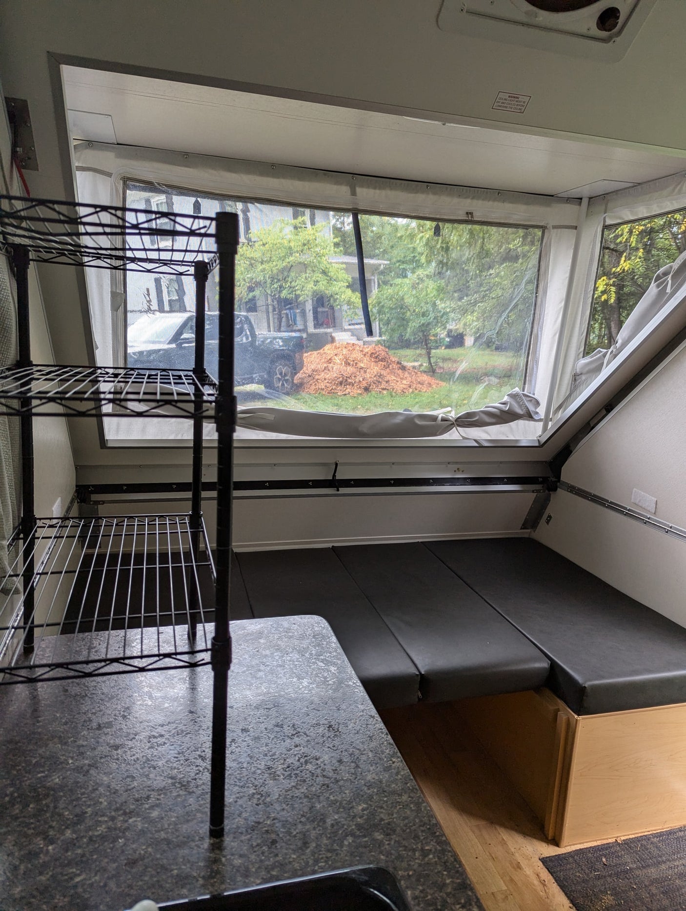 Inside an rv rental: functional camper living area with a bed, counter, and large windows revealing an outdoor scene.