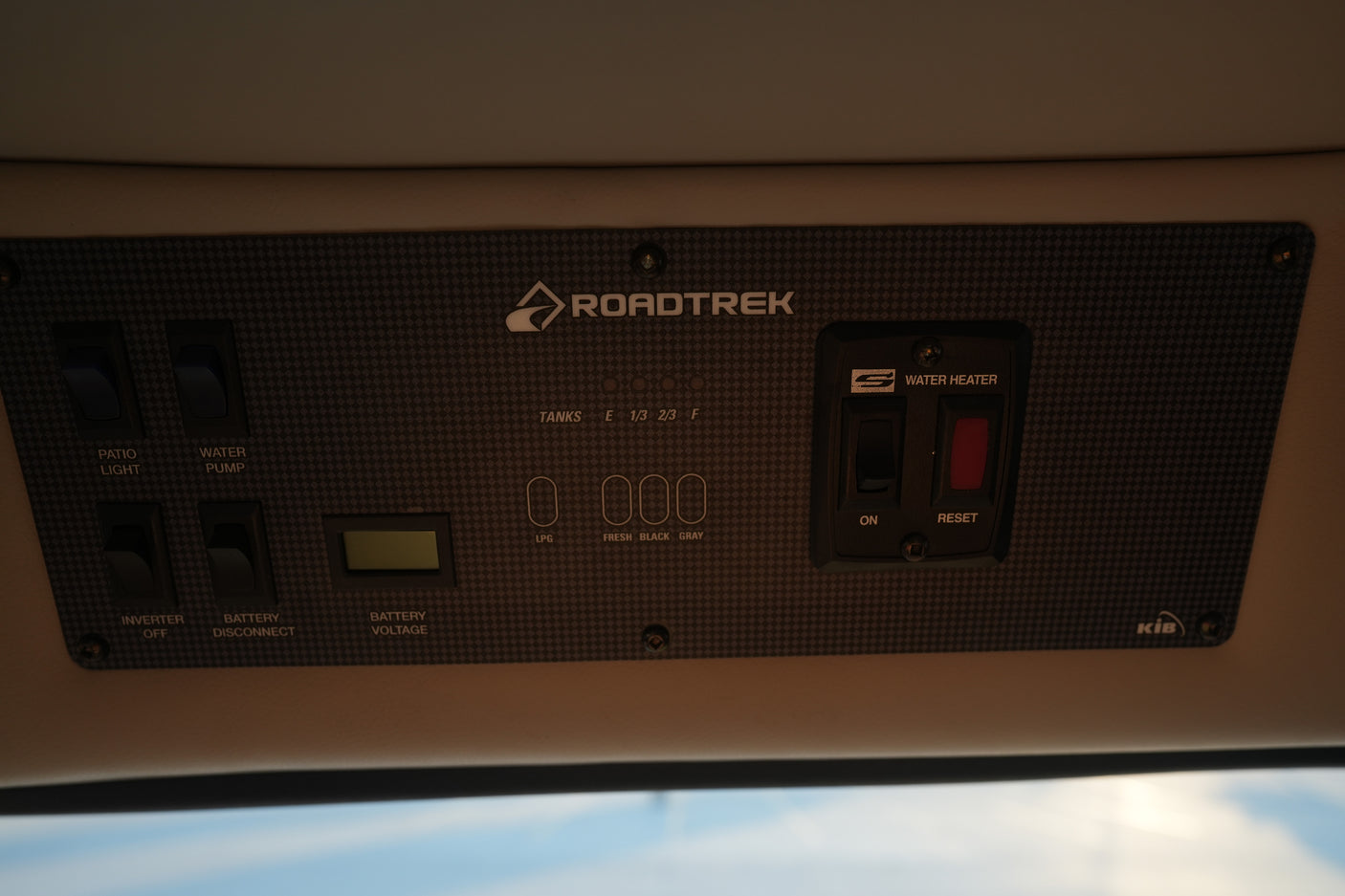 Inside an RV rental: Roadtrek control panel with water heater, tank levels, and battery voltage for essential functions.