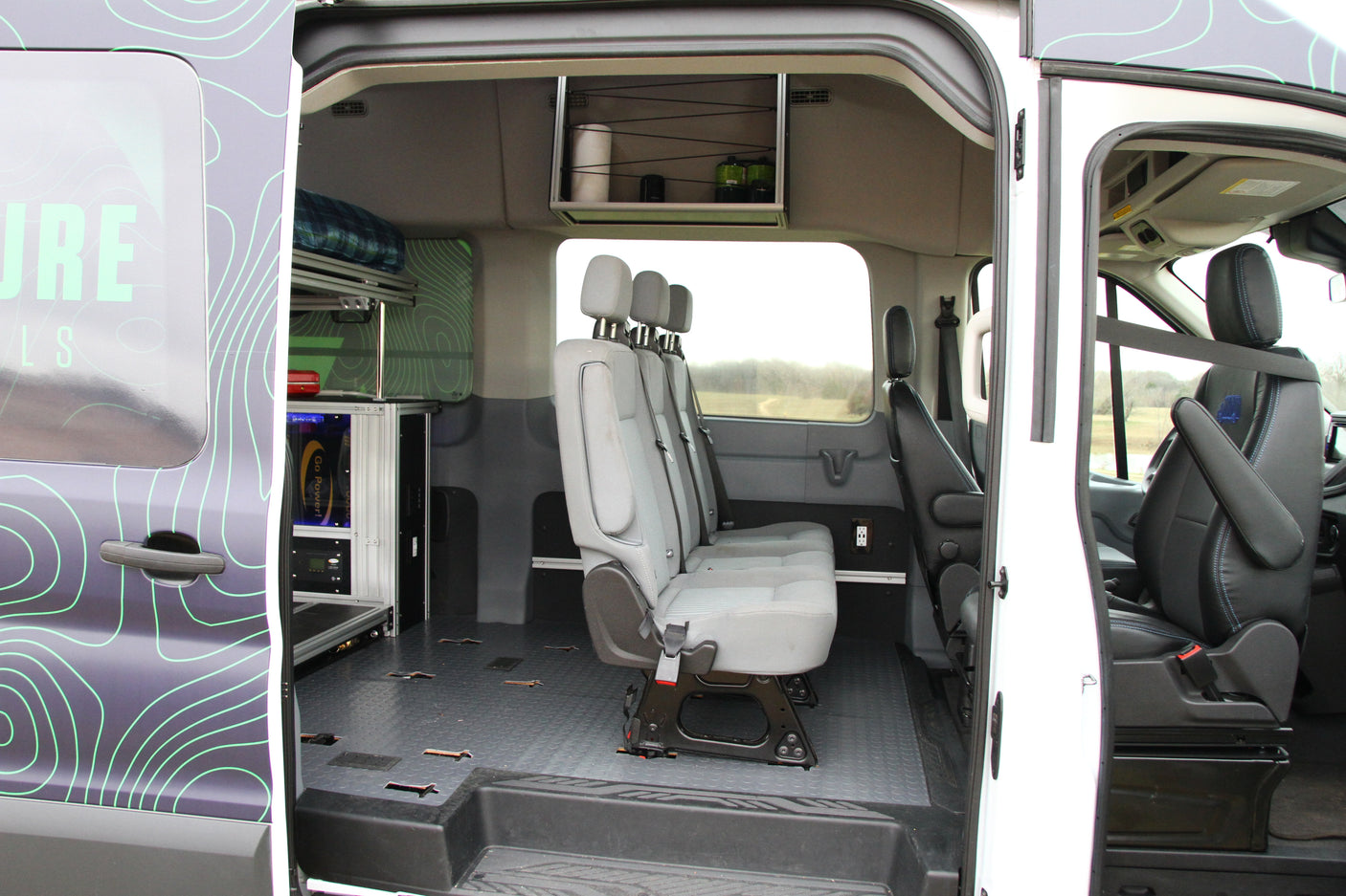RV rental van interior: gray bench seating, custom storage, and power equipment, ready for mobile adventures.