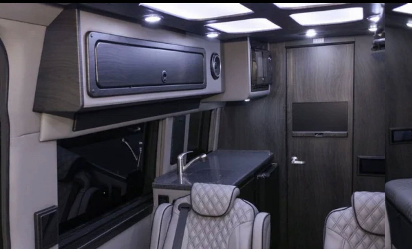 Experience a plush, custom **rv rental** interior featuring a kitchenette with a sink, microwave, TV, and comfortable seating. — photo 10