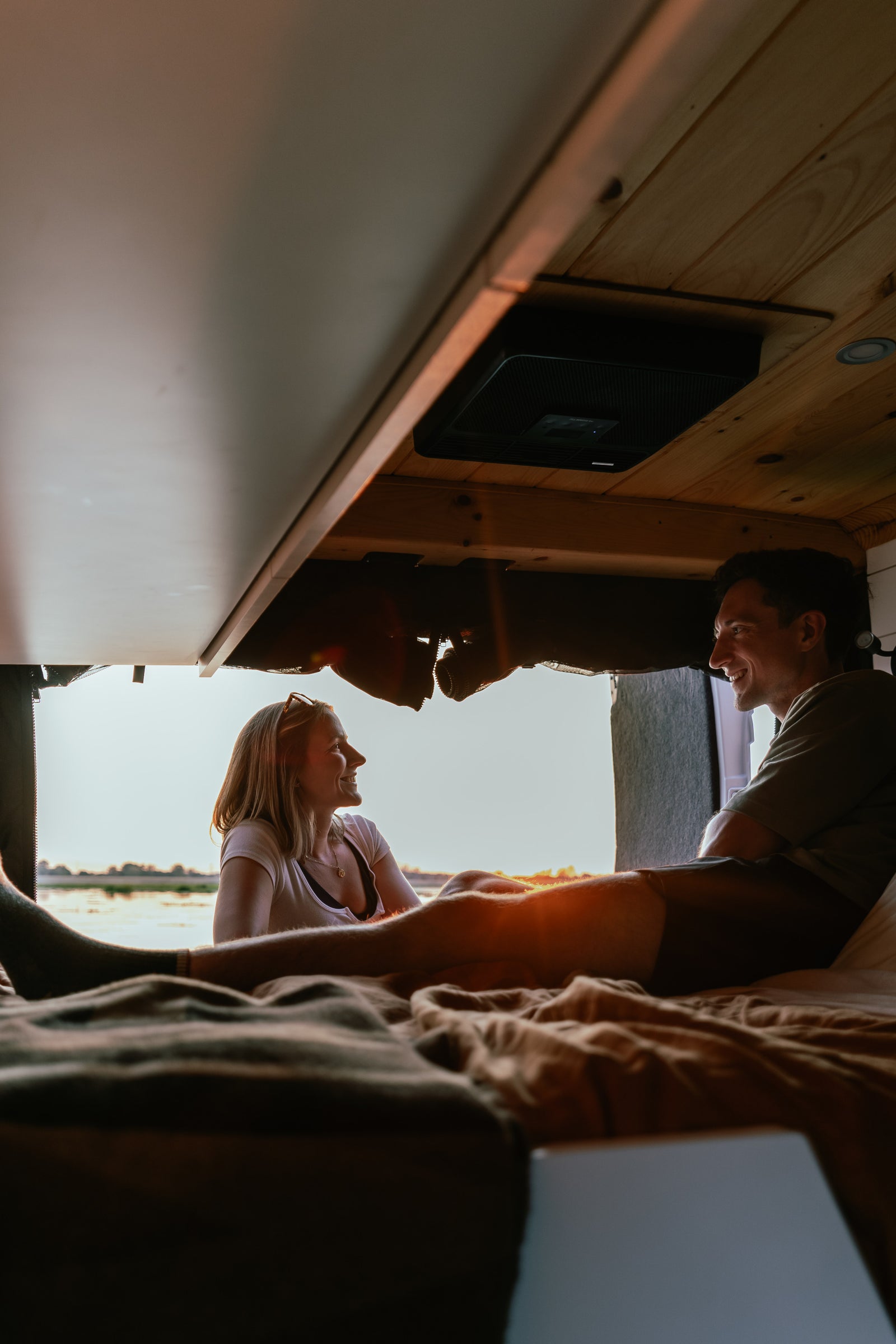 and compact water system under the counter.|White camper van (rv rental) with open side door showing a compact interior kitchen