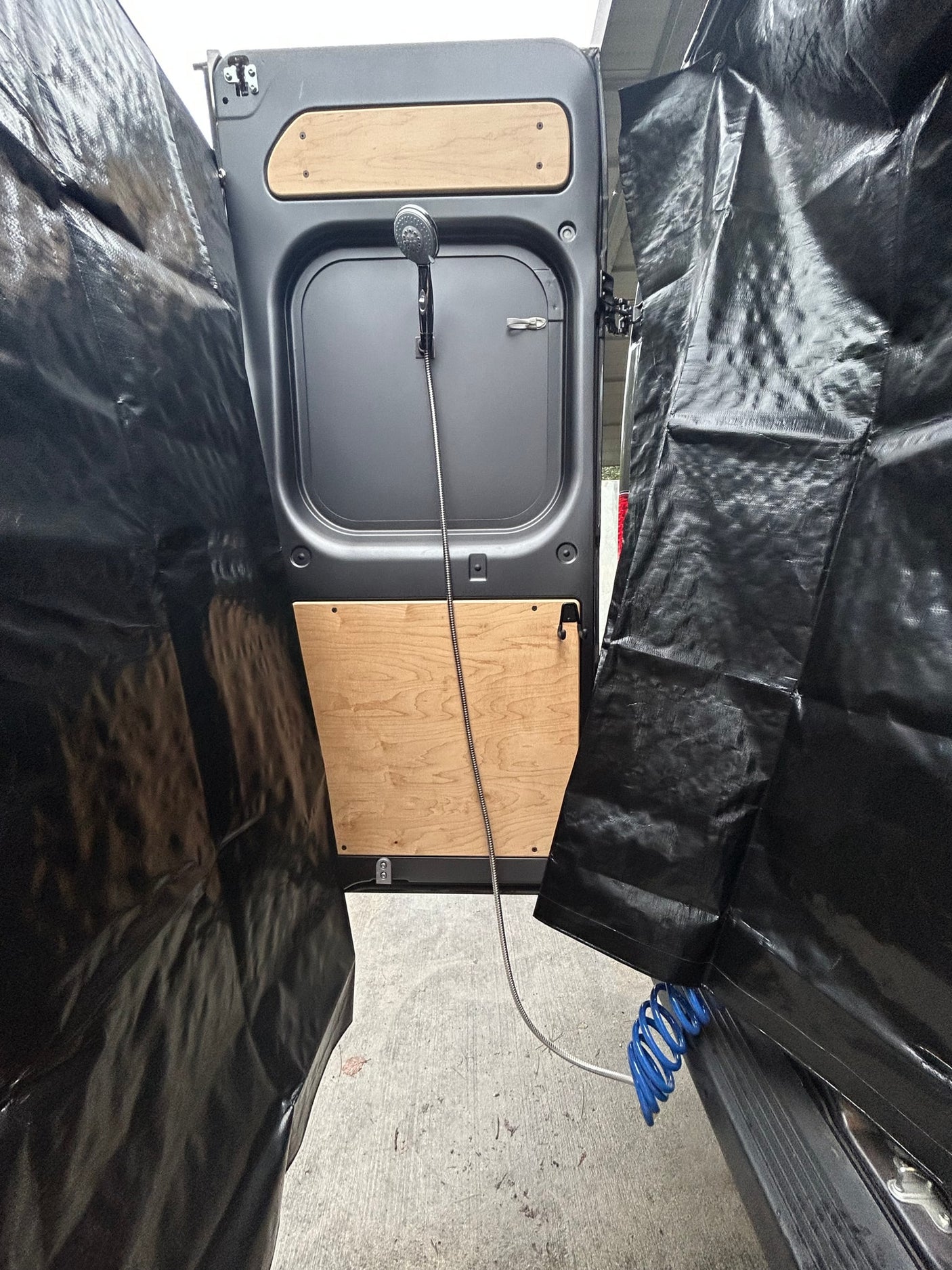 RV rental: Rear van doors with an outdoor shower and black privacy curtains, perfect for discreet bathing.