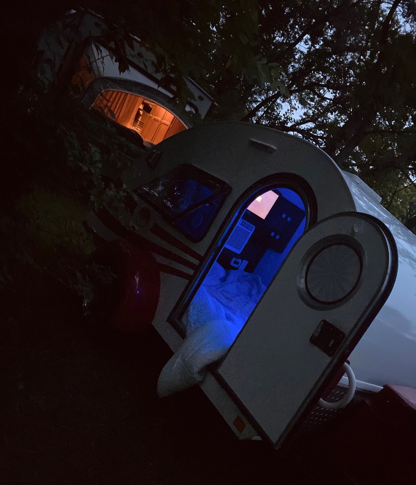 Cozy night camping in RV rental. Two teardrop trailers illuminate the darkness, one blue, one orange.