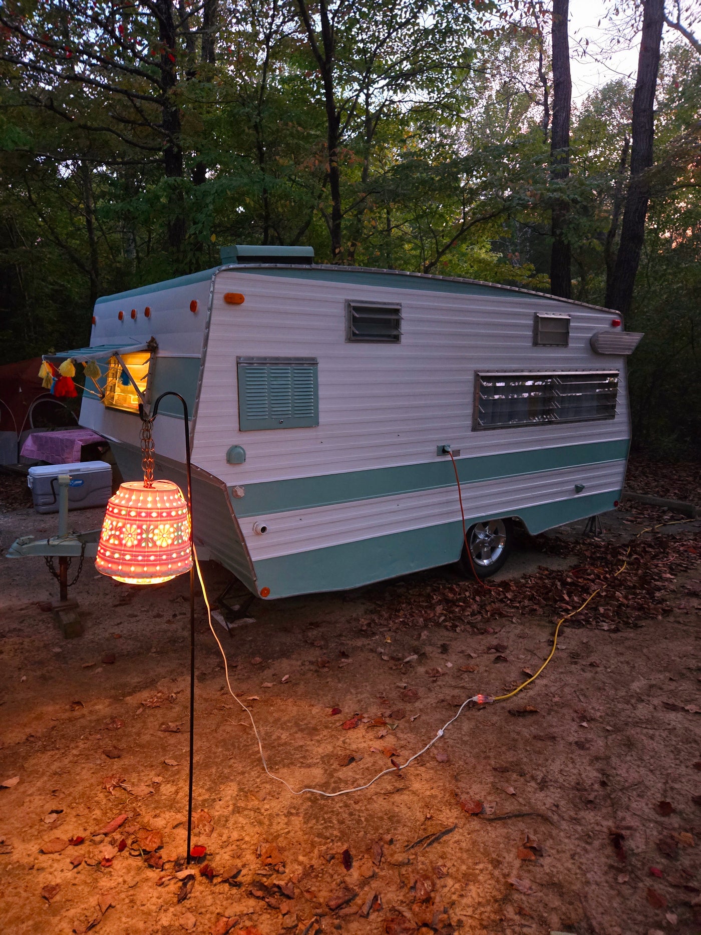 Enjoy a cozy evening in a vintage RV rental. This retro camper is nestled in a forest, illuminated by a glowing lantern. — photo 6