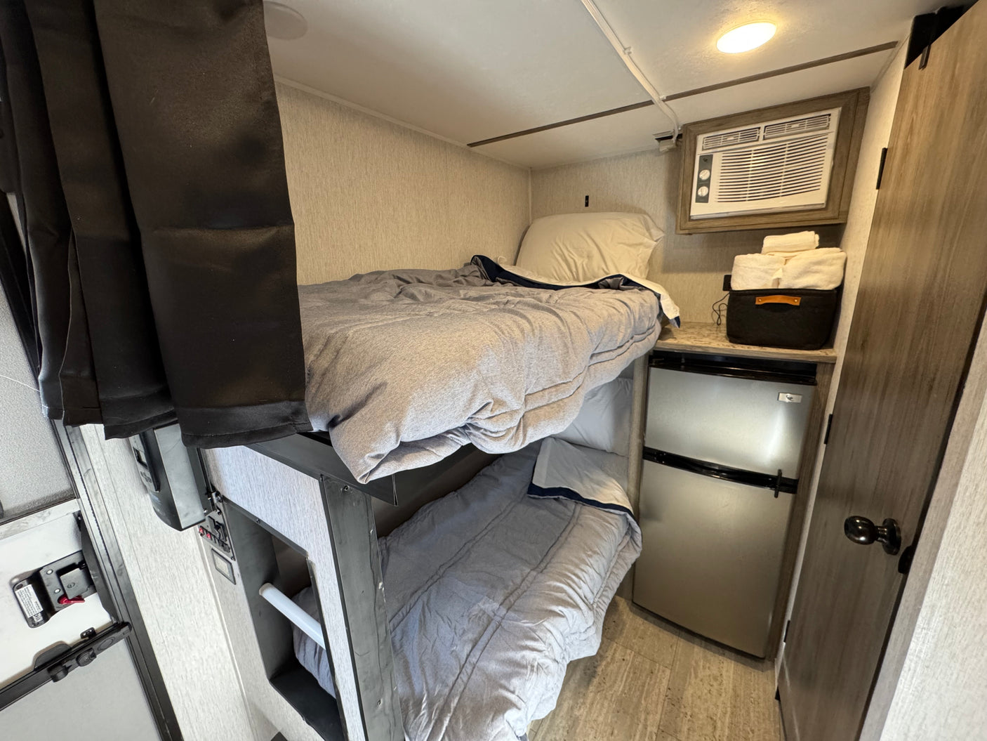 RV rental: Compact bunk beds with AC, mini-fridge, and fresh towels provide a functional sleeping area.