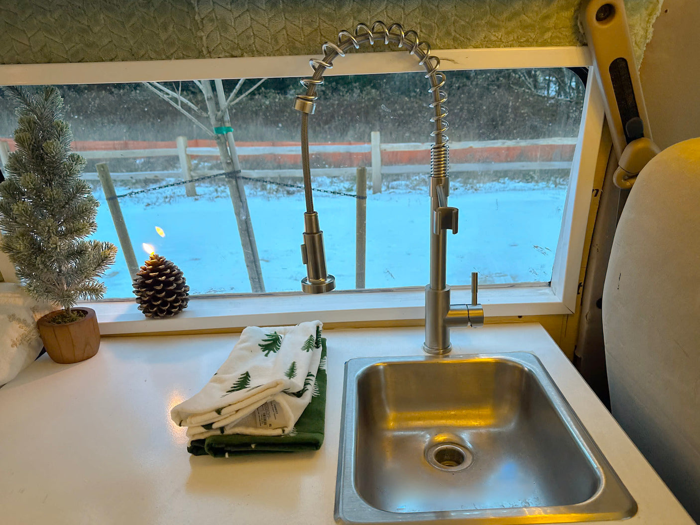 RV rental kitchen setup: sleek faucet, small sink, festive decor, and a peaceful snowy outdoor scene.