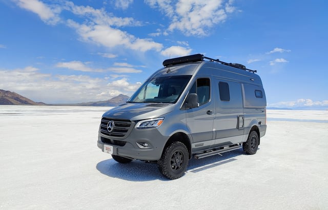 This grey Mercedes Sprinter van rv rental on vast salt flats under blue skies is perfect for your next off-road adventure trip.