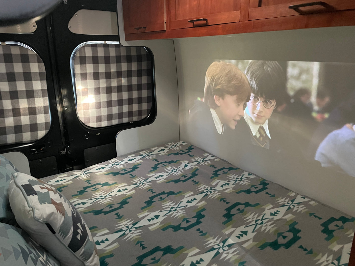 Experience an RV rental: a cozy bed with Harry Potter projected on the wall for epic movie nights on the go.
