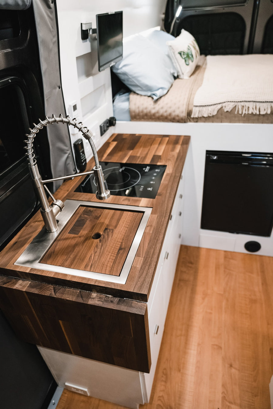 & power outlets in this modern camper van conversion.|This rv rental's modern interior features a sleek kitchen with induction cooktop